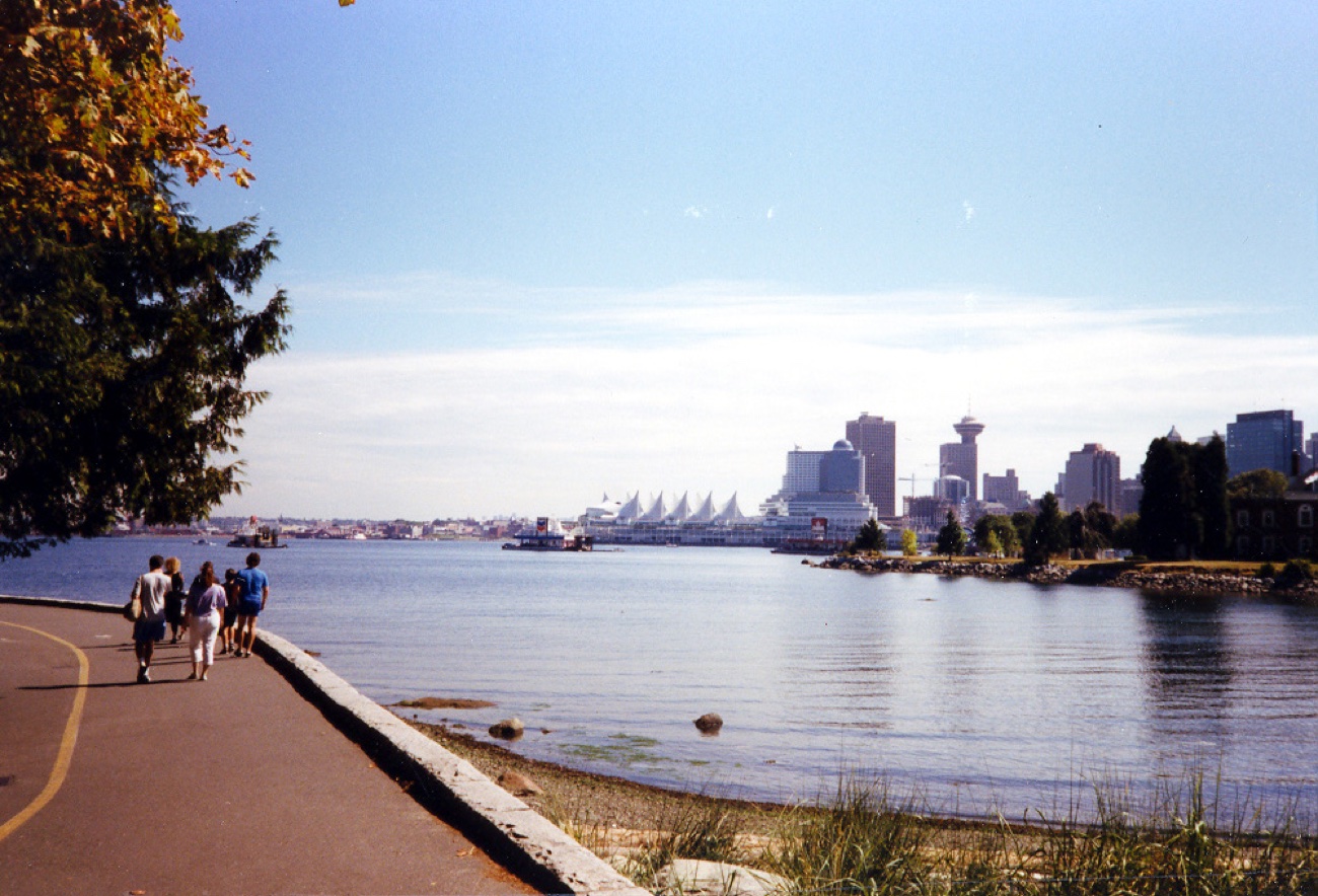 Vom Seawall im Stanley Park über Coal Harbour auf die Skyline von Vancouver, links die Segeldächer vom Canada Place